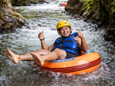 Cave tubing adventure in Ubud Bali with a tourist floating on a river surrounded by tropical jungle